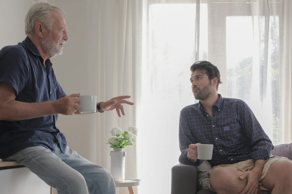 Older father and adult son having a thoughtful conversation at home