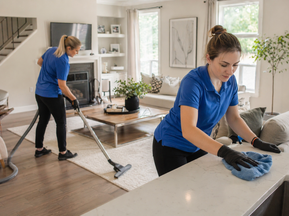 two professional cleaners working in a clean upscale home interior as part of a seasonal home cleaning checklist