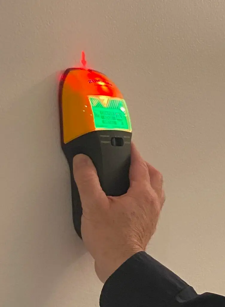 Stud finder scanning a drywall wall to accurately locate studs for safe mounting and installation work.