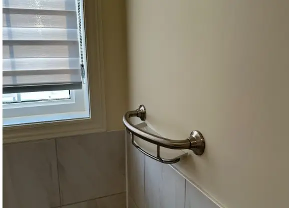 Chrome grab bar installed at edge of bathtub in Toronto bathroom