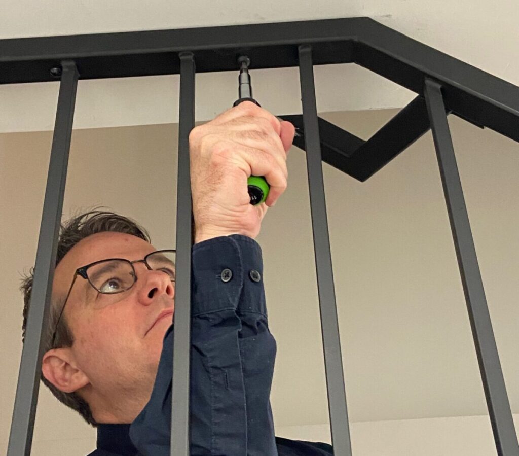 Technician installing a black metal indoor handrail on a staircase in a Toronto home