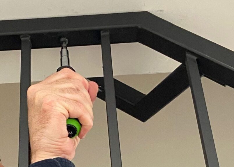 Technician installing a black metal indoor handrail on a staircase in a Toronto home
