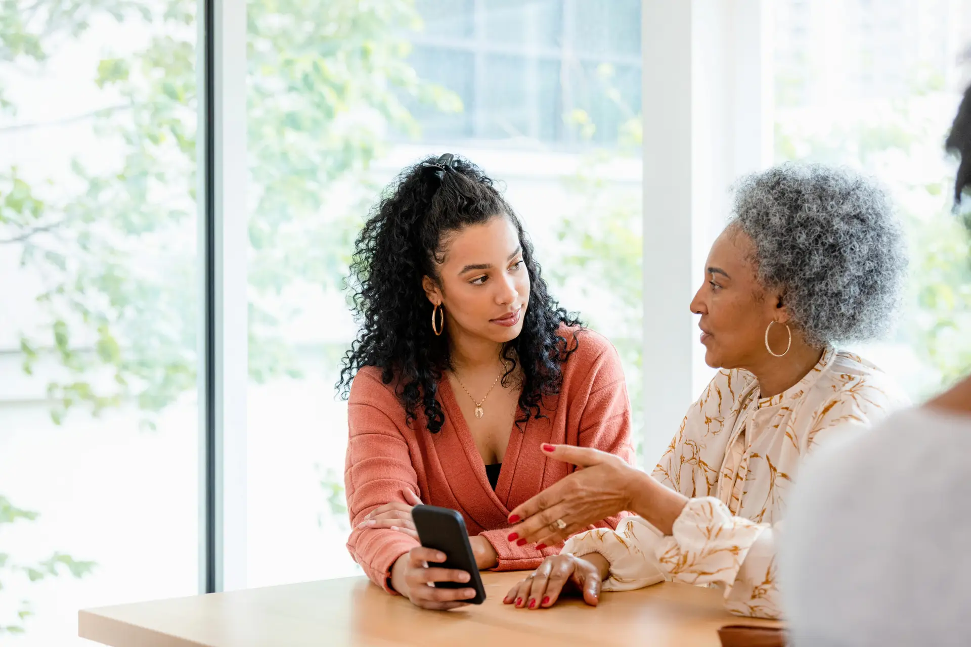 Adult daughter discussing home safety planning with elderly mother at kitchen table