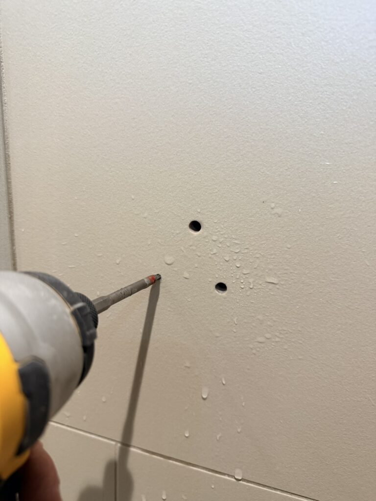 Drilling through bathroom tile for grab bar installation using a diamond drill bit and water cooling