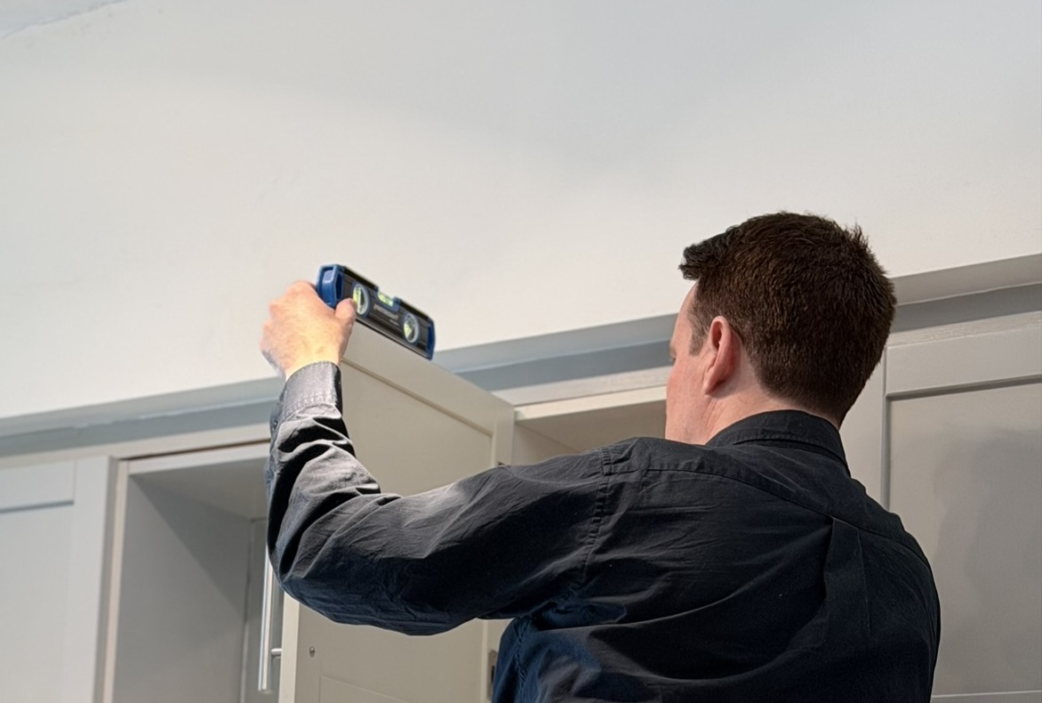 Handyman checking cabinet door alignment with a level during home maintenance in a Toronto home