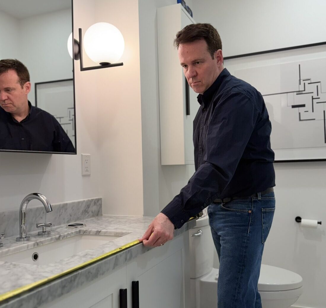 Handyman measuring bathroom vanity countertop before installation in a Toronto home