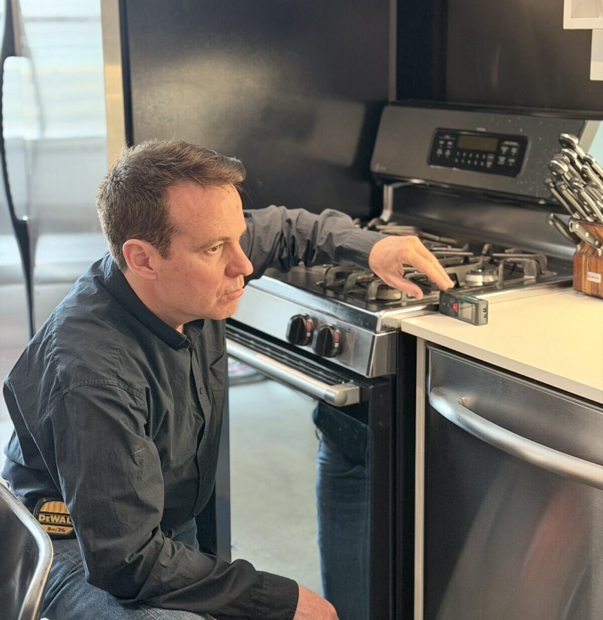 Toronto handyman measuring kitchen space with laser tool during installation work