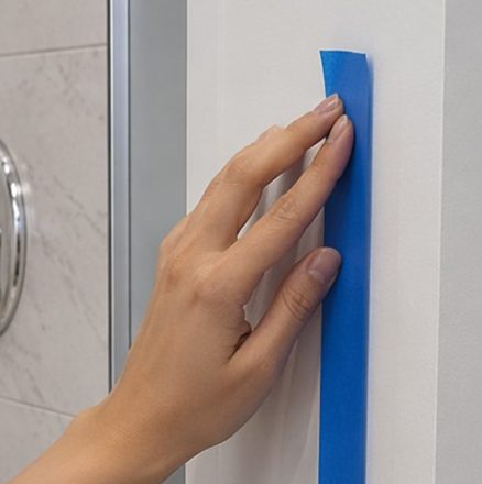grab bar installation guide showing hand marking vertical grab bar placement at shower entry with tape