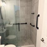 Modern walk-in shower with matte black grab bars and accessible bathroom safety features in Toronto home
