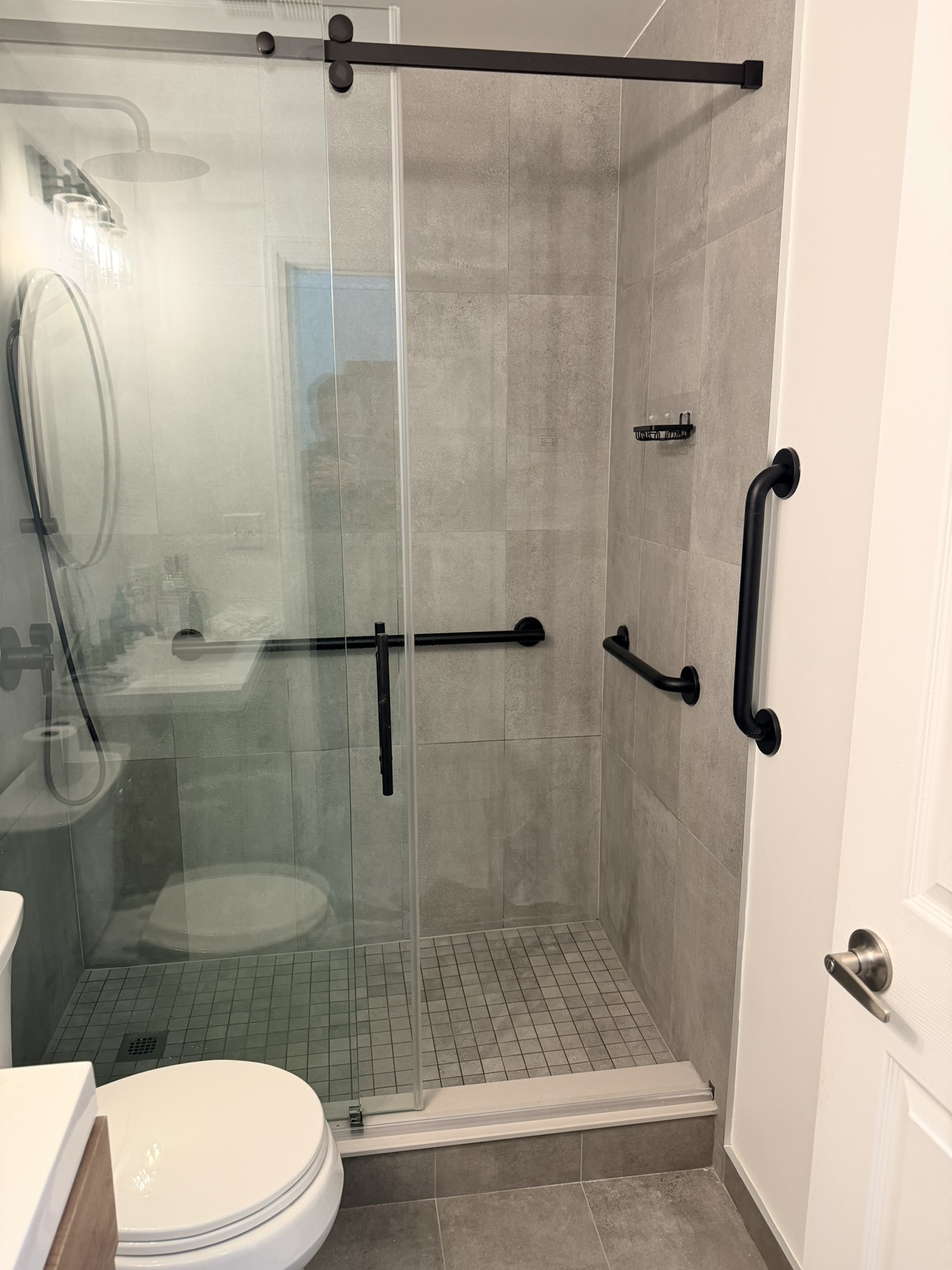 Modern walk-in shower with matte black grab bars and accessible bathroom safety features in Toronto home