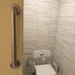 Vertical grab bar installed at walk-in shower entrance with shower seat for bathroom safety and accessibility in Toronto