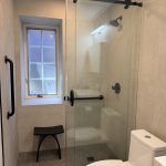 Matte black grab bars installed in a walk-in shower to improve bathroom safety while complementing modern black fixtures.