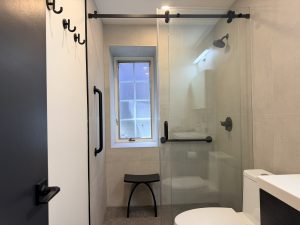 Matte black grab bars installed in a walk-in shower with built-in seating to improve bathroom safety and accessibility.
