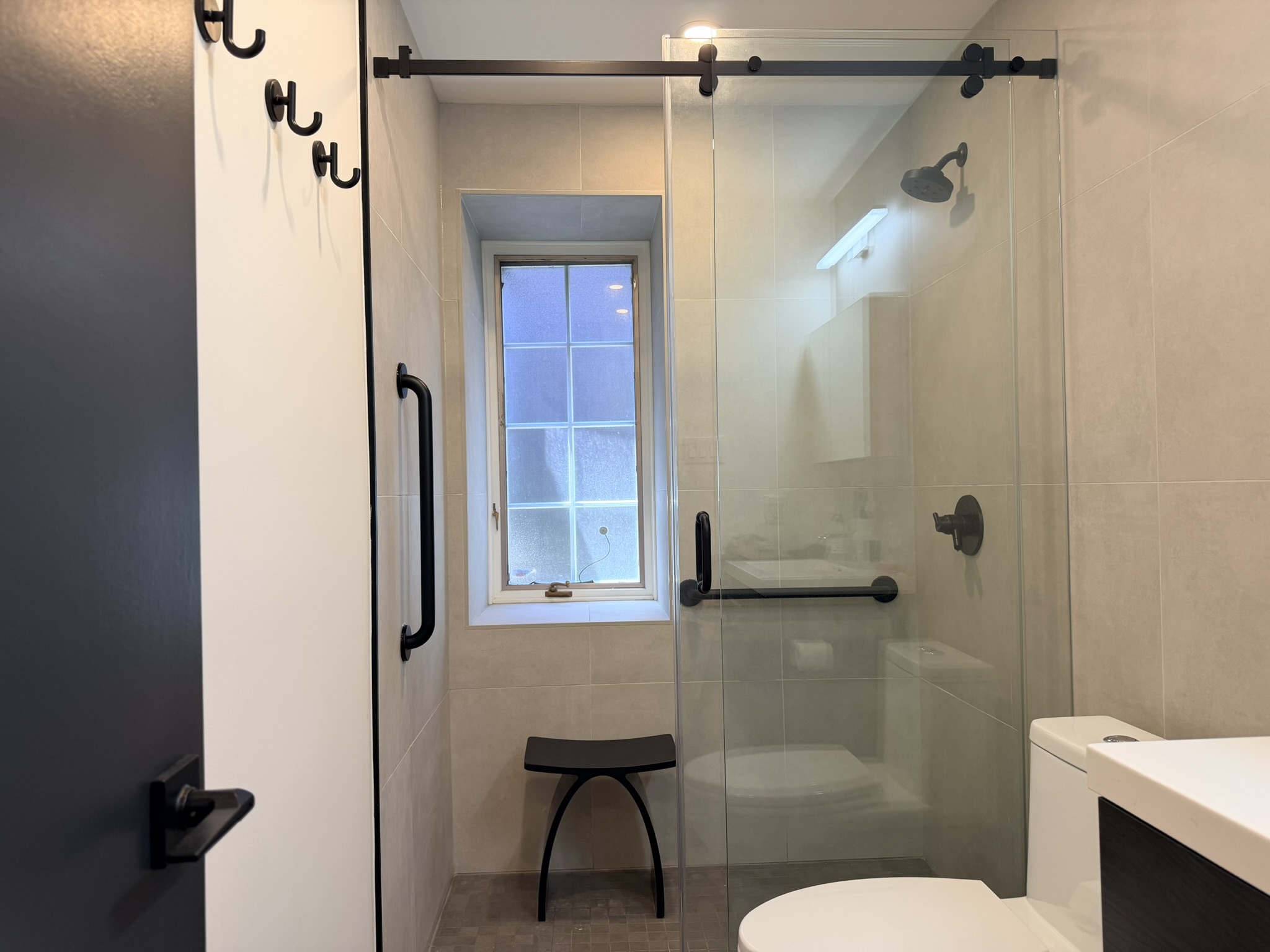 Matte black grab bars installed in a walk-in shower with built-in seating to improve bathroom safety and accessibility.